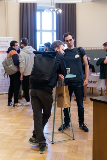 Attendees at a high table, one holding a Euruko Helsinki paper bag