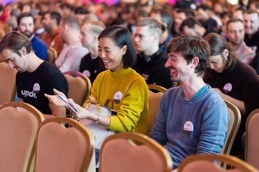 A man and a woman in the congress hall seats, laughing.