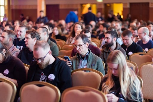 A photo of the crowd in the congress hall focused on a man looking at his phone